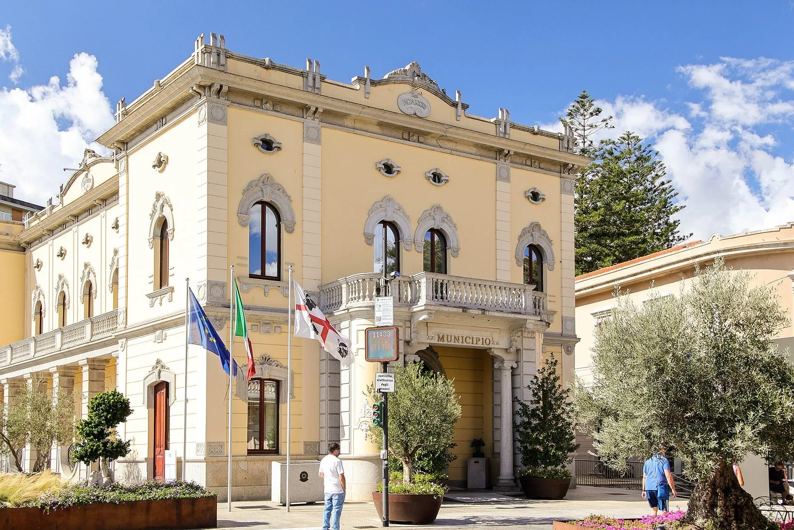 Il palazzo comunale di Olbia con la facciata chiara e le bandiere