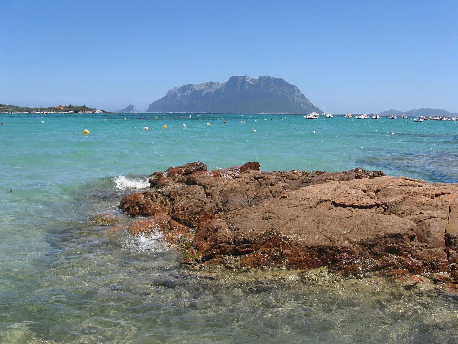 Spiaggia del golfo di Olbia con mare turchese e la sagoma di Tavolara all'orizzonte